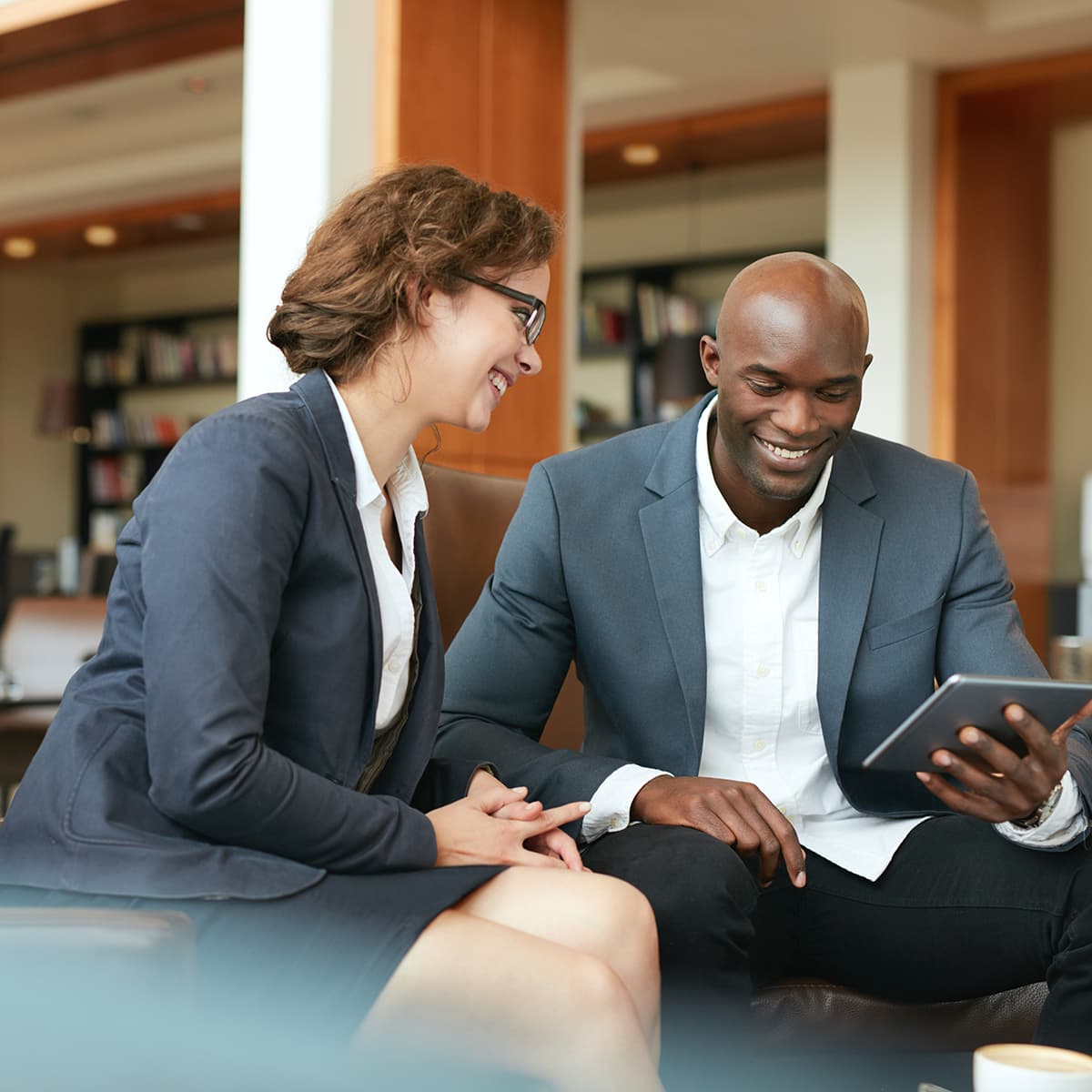 Smiling business people using digital tablet at coffee shop